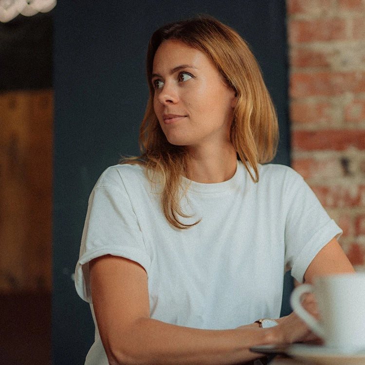 Woman enjoying coffee while reflecting on women's lifestyle tips in a cozy setting.