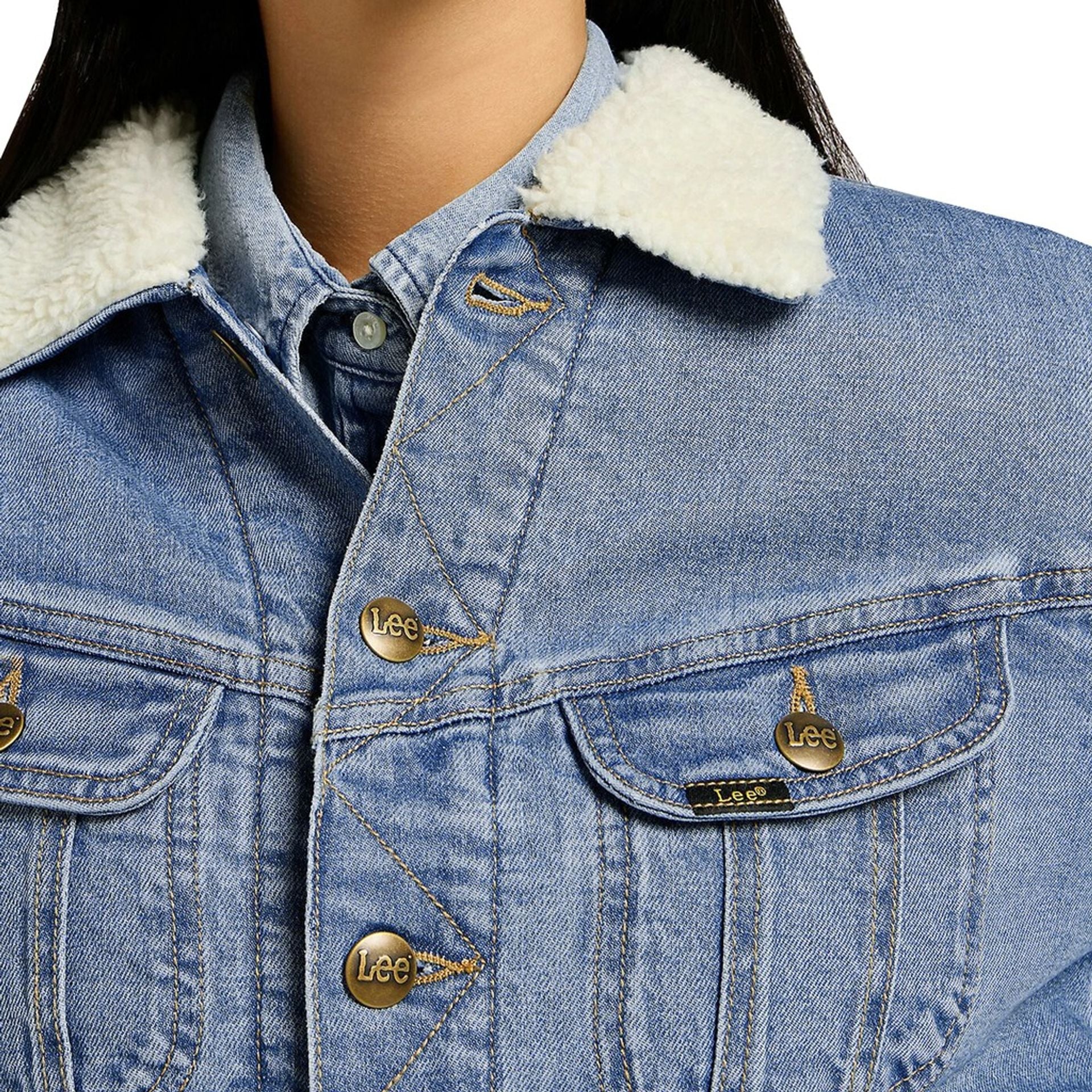 Close-up of a woman's Lee bomber jacket with a fur collar, showcasing the denim texture and brand details.